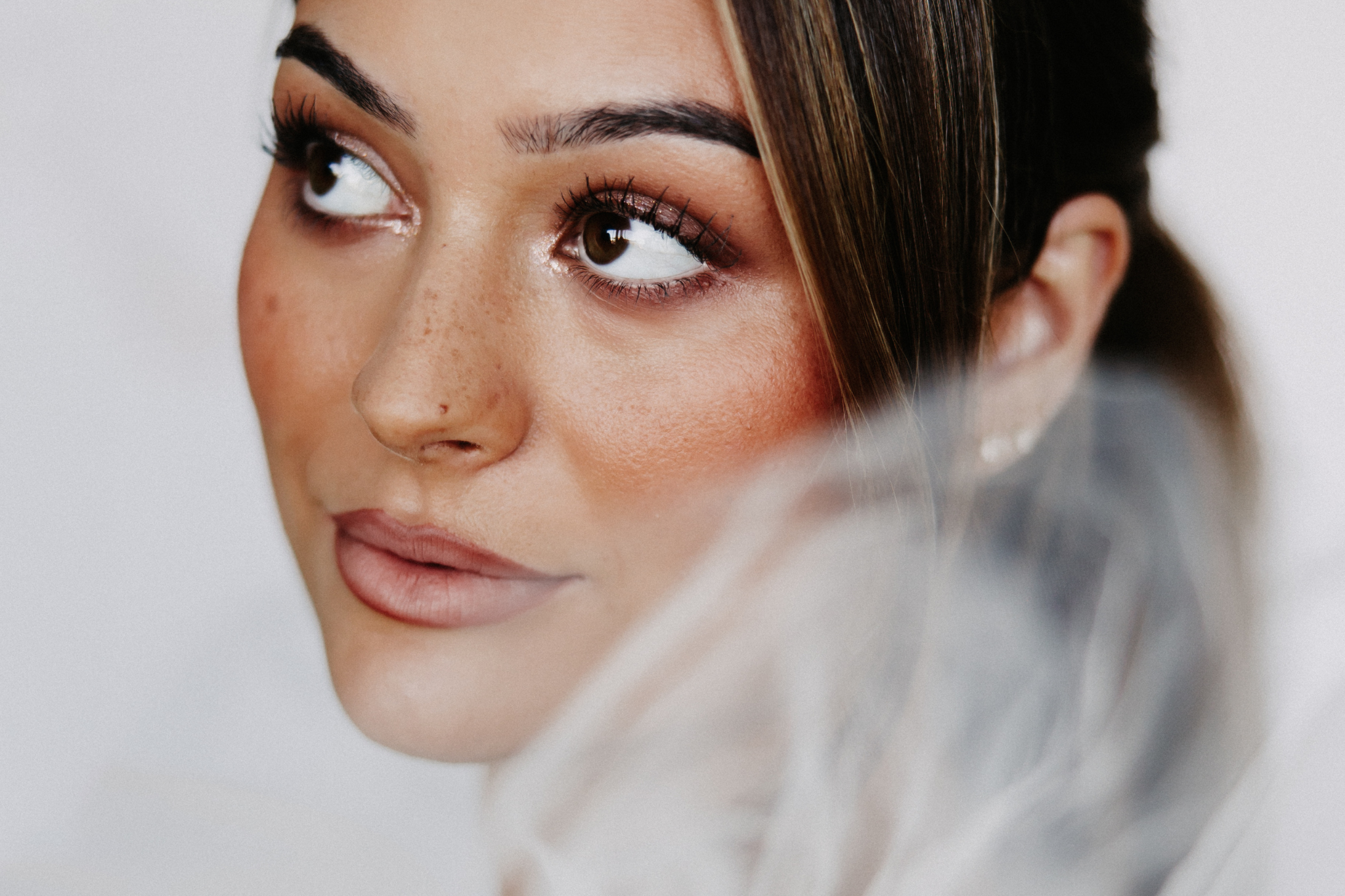 Close-up of a bride with glowing skin, dewy makeup, and soft neutral tones, showcasing healthy wedding day skin