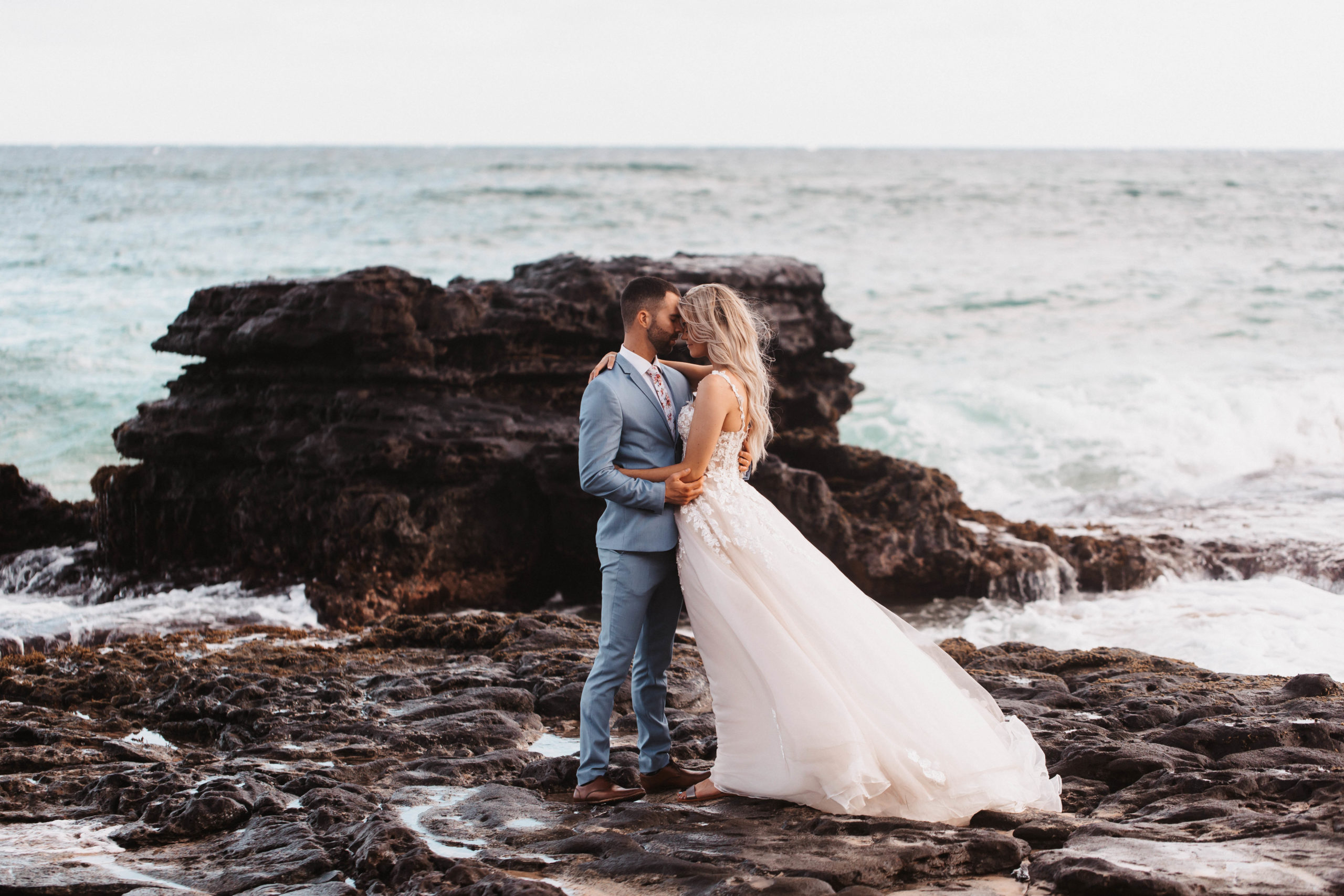 wedding couple at sandy beach hugging by the water
