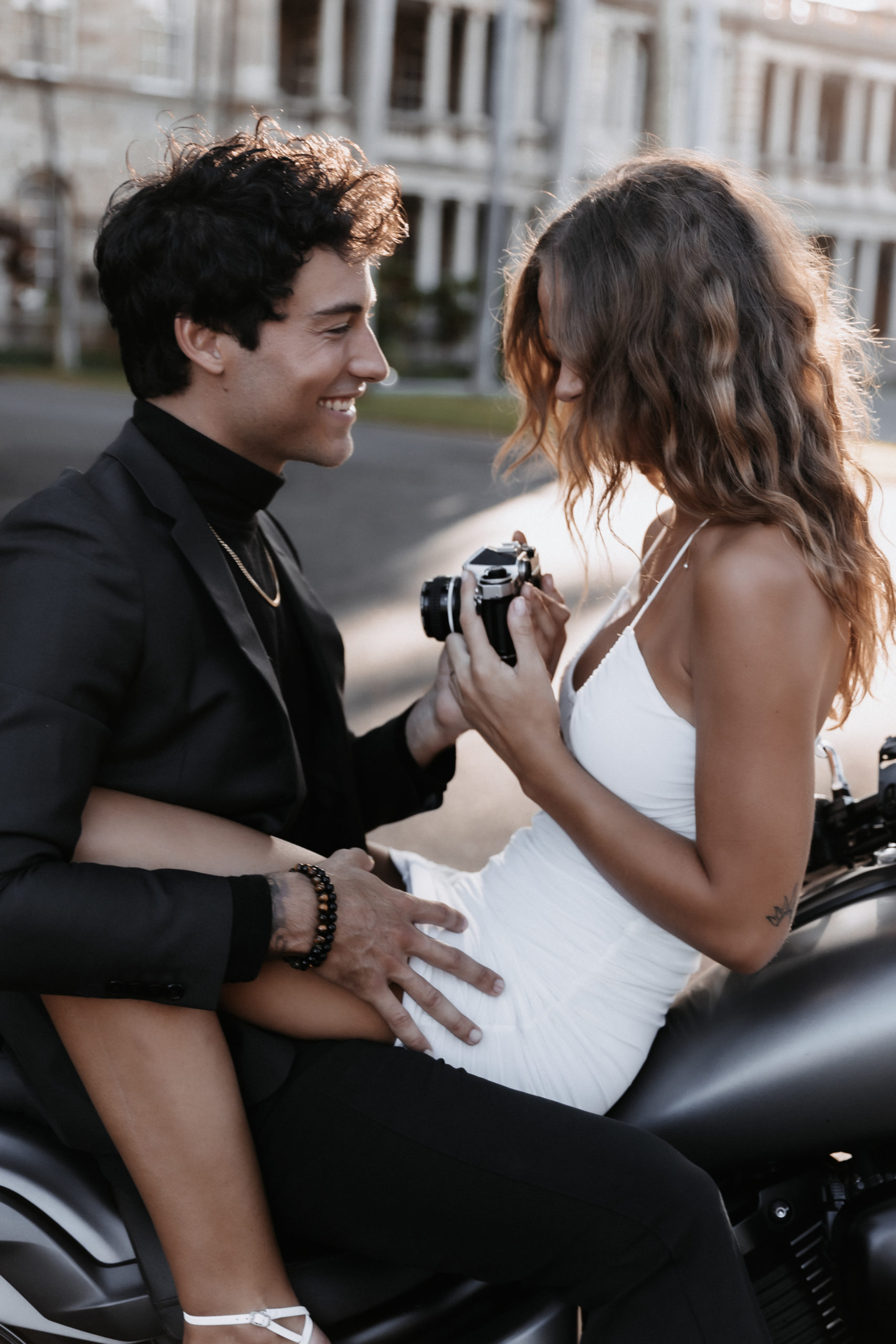 dressy city couple on motorcycle holding film camera