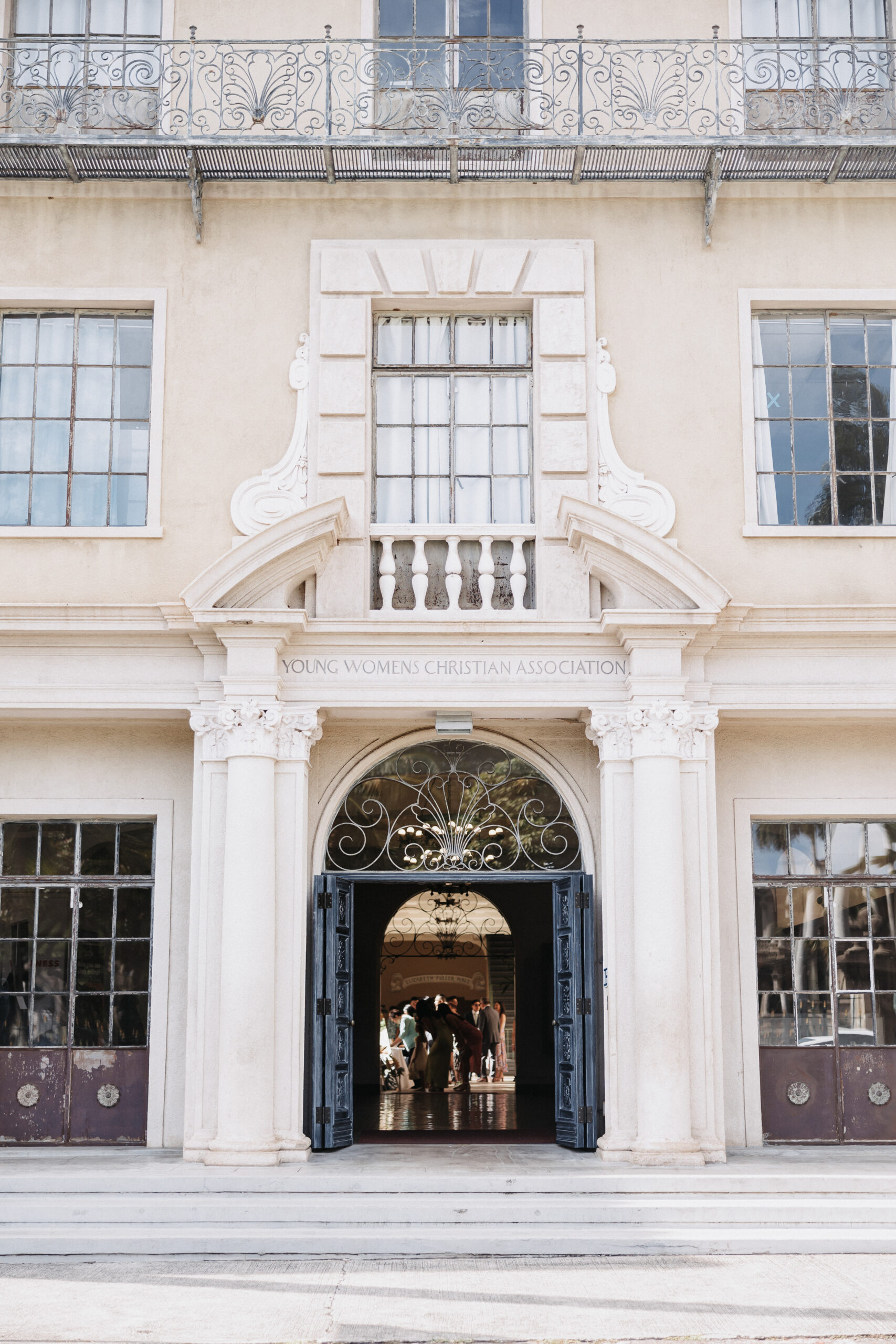 The front of a building with European architecture, the doors are open and there are people inside