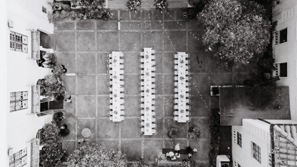 Drone view of Cafe Julia wedding reception in Honolulu with long tables set in the courtyard, showcasing one of the best Hawaii wedding venues for intimate gatherings
