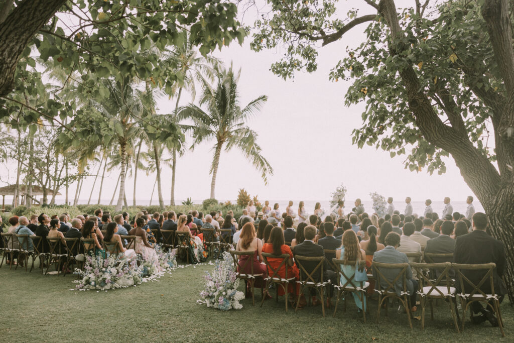 Outdoor wedding ceremony at Lanikuhonua in Hawaii with ocean backdrop and tropical greenery, photographed by a local Hawaii wedding photographer