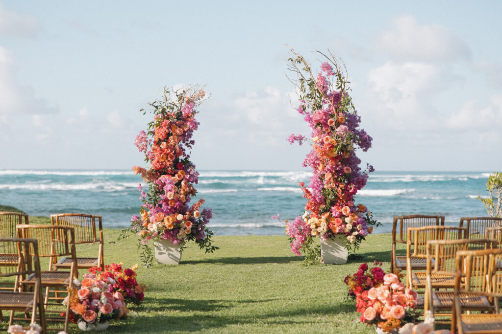 Bright floral wedding ceremony arch set against the ocean backdrop at Loulu Palm on Oahu’s North Shore.