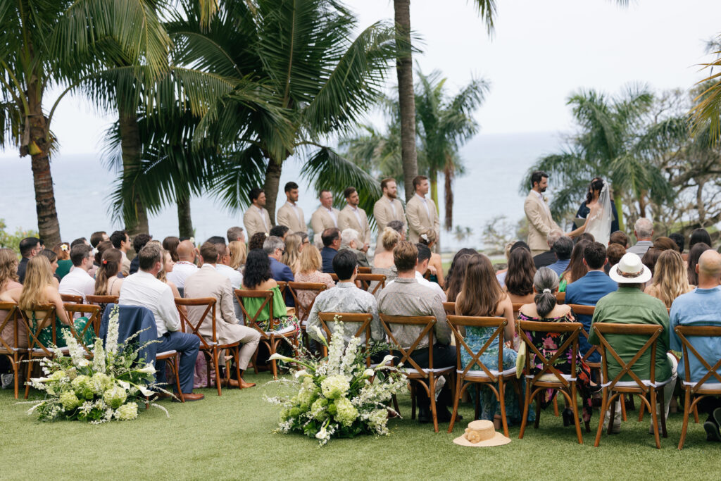 Oceanview wedding ceremony at Kualoa Ranch Paliku Gardens in Oahu, Hawaii with palm trees and lush florals