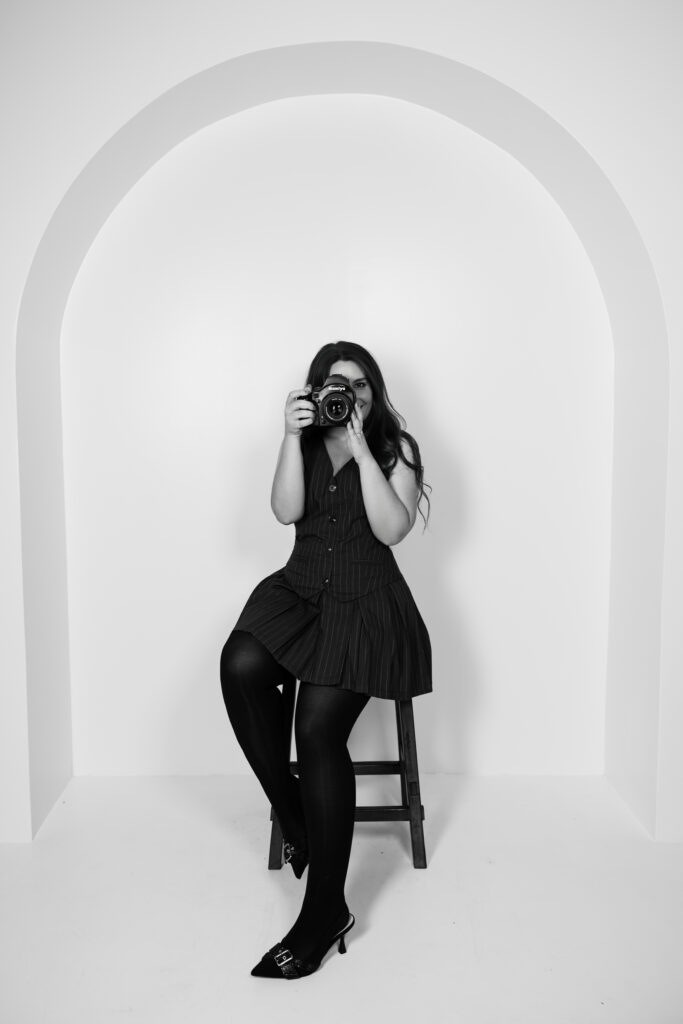 Amari Marie self-portrait holding camera in minimalist studio arch