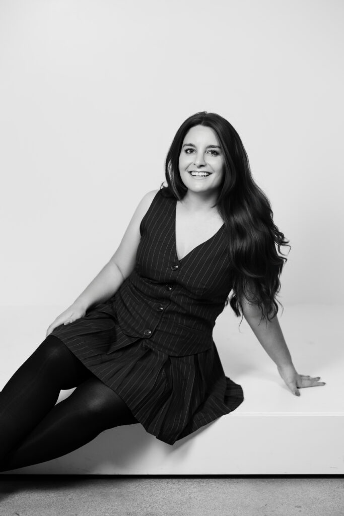 Amari Marie smiling in studio portrait wearing pinstripe dress